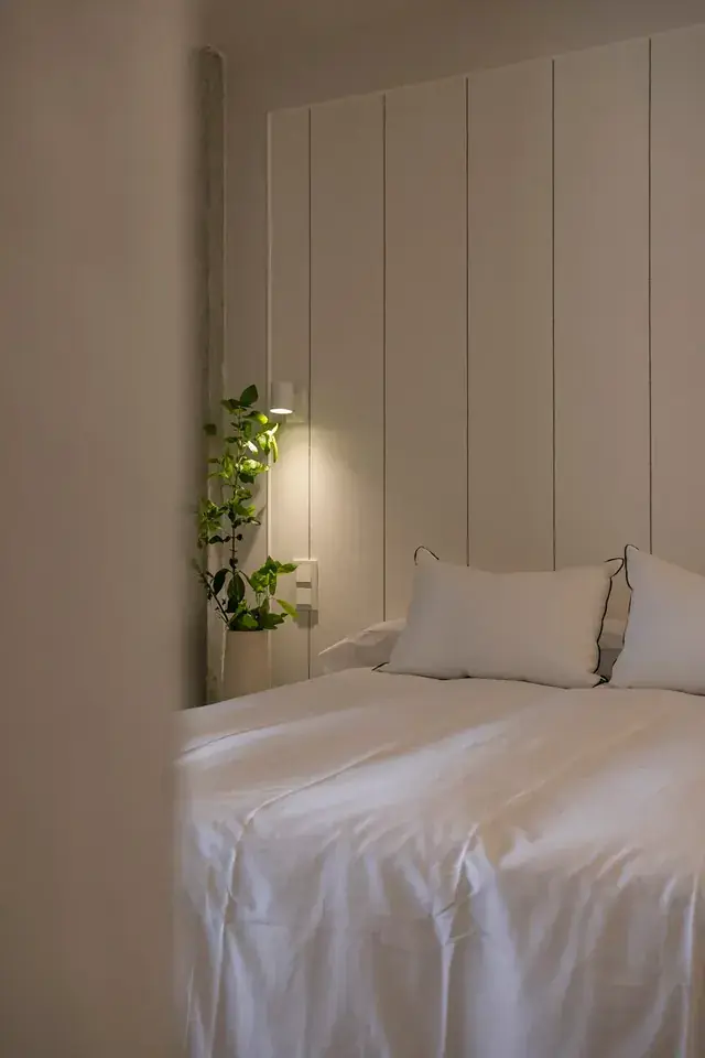 Dormitorio principal con paneles de madera clara y textiles naturales